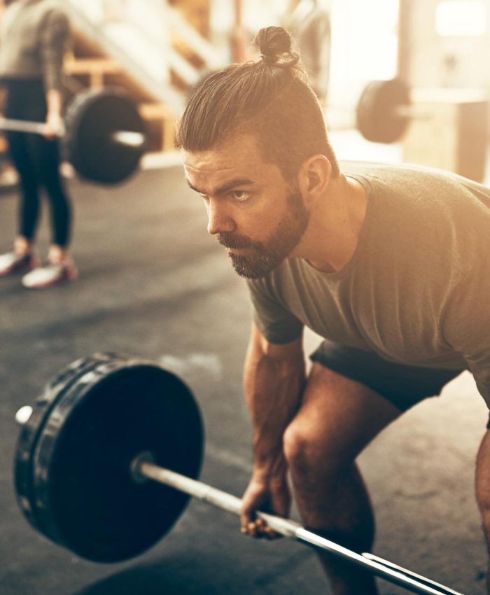 Fit young man in sportswear preparing to lift weights during an exercise session in a gym