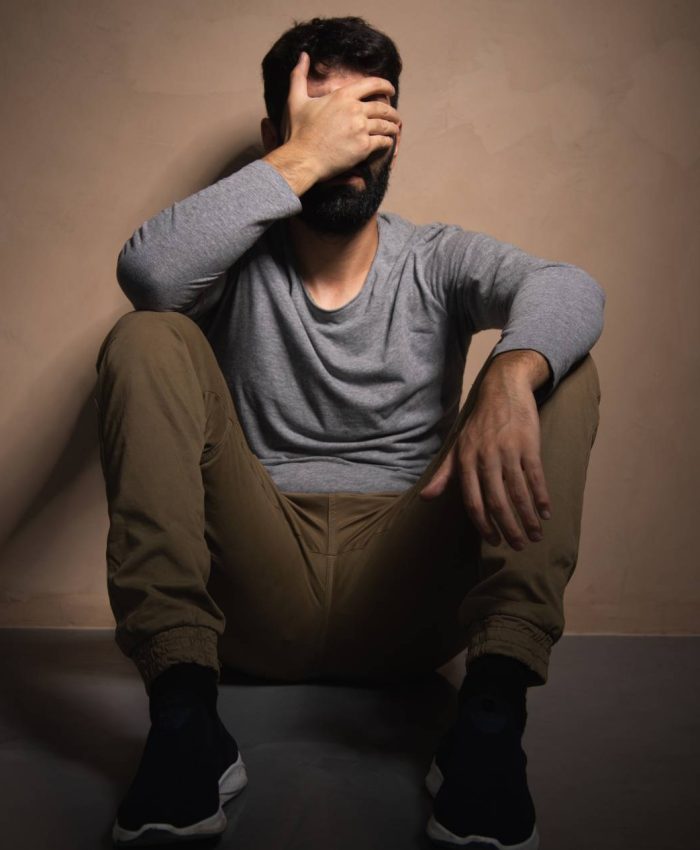 Man sadly sitting on the floor covering his face